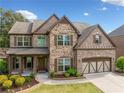 Charming two-story home with a brick and stone facade, landscaped front yard, and a two-car garage at 2435 Sentinel Chase Way, Cumming, GA 30041
