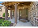 Inviting front porch with stone columns, a brick facade, and a decorative front door with sidelights at 2435 Sentinel Chase Way, Cumming, GA 30041