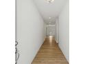 A bright hallway featuring wood flooring and white walls leading to other rooms in the home at 7252 Eton Ln, Locust Grove, GA 30248