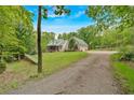 View of home on the lot featuring brick siding, green metal roof, and a long gravel driveway at 4332 Brushy Mountain Rd, Rockmart, GA 30153