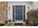 Inviting front door with decorative sidelights, stone accents, and blooming flowers at 979 Bridgegate Ne Dr, Marietta, GA 30068