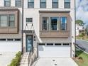 A two story townhome with white brick facade, a bay window, and a one car garage at 2171 Burnside Dr Nw, Atlanta, GA 30318
