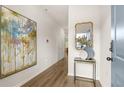 Well-lit hallway with wood floors featuring modern art and an accent table with mirror at 9452 Pinecrest Path # 314, Jonesboro, GA 30238