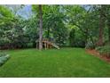 Sprawling backyard featuring lush green grass, mature trees, and a wooden playset perfect for outdoor fun at 1349 Middlesex Ne Ave, Atlanta, GA 30306