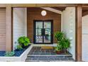Close up of a welcoming front porch with beautiful stone floors, a light fixture, and greenery at 5785 Timberlane Ter, Sandy Springs, GA 30328
