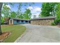 Single-story home with stone accents, blue siding, a circular driveway, and a lush green lawn at 5742 Harbor Dr, Buford, GA 30518