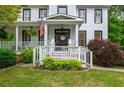 Charming two-story home with a welcoming front porch, American flag, and beautiful landscaping at 1161 Arborhill Dr, Woodstock, GA 30189