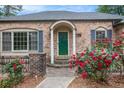 Brick home with a green front door framed by columns and vibrant red roses at 2790 Westhampton Way, Tucker, GA 30084