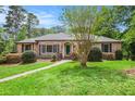 Charming brick home featuring a lush green lawn, mature trees, and colorful landscaping at 2790 Westhampton Way, Tucker, GA 30084