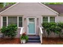 Close-up of a home's entrance, showing a turquoise door, updated landscaping, and brick details at 2599 E Tupelo Se St, Atlanta, GA 30317