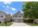 Two-story home featuring gray siding, a two-car garage, and a landscaped front yard with a mature shade tree at 5830 Sterling Ct, Cumming, GA 30040