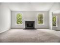 Spacious living room with a cozy fireplace, large windows, and neutral carpeting at 1024 Odelle Cir, Mcdonough, GA 30253
