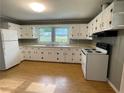 Bright kitchen with white cabinets, laminate flooring, and essential appliances for convenient meal preparation at 66 Lakeshore Dr, Bowdon, GA 30108