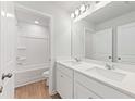 Bright bathroom featuring double sinks, a large mirror, modern lighting, and a shower-tub combination, all in a clean, white design at 7133 Brushwood Bend (Lot 43), Lithonia, GA 30058