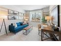Bright living area featuring a comfortable blue sofa, neutral carpet, and a work space at 7145 Brushwood Bend - Lot 41, Lithonia, GA 30058