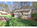 Inviting home with stone accents, green siding, and a circular driveway surrounded by a lush green lawn at 875 Waterbrook Ct, Roswell, GA 30076