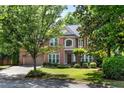 Brick home with an attached garage surrounded by trees, green grass, and lush landscaping at 486 Milledge Gate Se Ter, Marietta, GA 30067