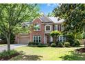 Traditional brick home featuring an attached garage, mature trees, and a well-maintained green lawn at 486 Milledge Gate Se Ter, Marietta, GA 30067