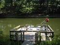 Lakefront dock with seating, table, and a lift provides a relaxing space to enjoy the natural surroundings at 8145 Stone Hill Rd, Cumming, GA 30028