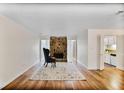 Open-concept living room showcasing a stone fireplace and hardwood floors, with a view into the kitchen at 8740 Roswell Rd # 9C, Atlanta, GA 30350