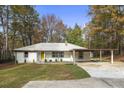 Charming single-story home features a yellow door and attached carport, nestled among mature trees at 2013 Ridge Rd, Dallas, GA 30157