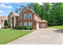 A spacious, two-story brick home with attached garage and a wide driveway, surrounded by lush greenery at 305 Spooner Dr, Mcdonough, GA 30252
