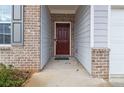 Inviting front entrance featuring a brick surround, a maroon front door, and gray siding at 340 Paulownia Cir, Mcdonough, GA 30253
