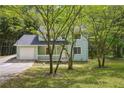 Two-story home with light green siding, white trim, and an attached garage nestled among mature trees at 3688 Burnley Court, Lithonia, GA 30038
