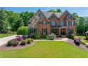 Charming two-story home with brick and stone facade, lush lawn and decorative landscaping at 5925 Boulder Bluff Dr, Cumming, GA 30040