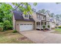 Side view of home featuring a two-car garage and a covered front porch at 1912 Riverton Dr, Suwanee, GA 30024