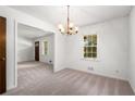 An open-concept dining room featuring a classic chandelier and neutral carpet at 4444 Bending River Sw Trl, Lilburn, GA 30047