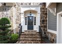 Elegant front entrance with stone steps, a black door with glass panels, and manicured greenery at 185 Windsor Cv, Sandy Springs, GA 30328