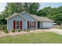 Inviting home exterior features a well-kept lawn, red shutters, an attached garage and manicured landscaping at 2889 Estuary Dr, Acworth, GA 30101
