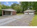 View of two garages, one carport and one detached with white doors and brick exterior, on a paved driveway at 509 Woodland Ln, Lawrenceville, GA 30043