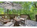 Outdoor living space features a striped umbrella, a comfortable wicker set, and scenic forest views at 2185 Arbor Chase, Cumming, GA 30041