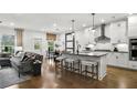 Open-concept living room and kitchen with hardwood floors, modern lighting, and stylish furnishings at 5230 Hyde Rd, Cumming, GA 30040