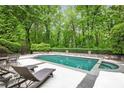 Backyard pool with a spa and lounge chairs, surrounded by lush greenery and a stone patio at 4356 N Buckhead Ne Dr, Atlanta, GA 30342