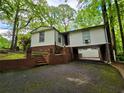 Home featuring a unique carport design with brick supports and a lush, green wooded backdrop at 1720 Valley Ln, Cumming, GA 30040
