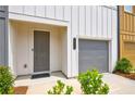 A close-up exterior view of a modern townhome with a gray front door and an attached garage at 1624 Gunnin Nw Trce, Atlanta, GA 30318