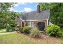Quaint brick home with a curved roofline, arched entryway, screened in porch, and green lawn at 1791 Melrose Sw Dr, Atlanta, GA 30310