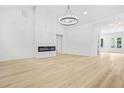 Spacious and modern living room with a fireplace, wood floors, a stylish chandelier, and white walls at 225 Alcovy Cir, Covington, GA 30014