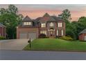 Beautiful brick two-story home featuring a well-manicured front lawn and a two-car garage at dusk at 3341 Cranmore Chase, Marietta, GA 30066