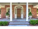 Classic brick home entrance with columns, decorative accents, and a wooden front door with stone porch at 3845 Parian Nw Rdg, Atlanta, GA 30327