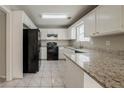 Bright kitchen features granite countertops, tile flooring, white cabinets, and black appliances at 6351 Stablewood Way, Lithonia, GA 30058