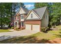 Angle view of the charming two-story brick home and two car garage, with manicured lawn and shade trees at 310 Woodbrook Crst, Canton, GA 30114