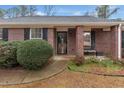 Close-up of a brick facade with black shutters and a welcoming front porch with bench at 10 Mcgiboney Pl, Covington, GA 30016