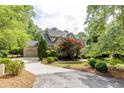 Brick and stone home boasts a manicured lawn, mature trees, and a side-entry three car garage at 1575 Spalding Dr, Sandy Springs, GA 30350