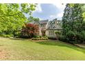 Charming brick home featuring a manicured lawn, mature trees, and classic architectural details at 1575 Spalding Dr, Sandy Springs, GA 30350