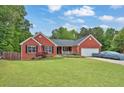 Attractive brick home with a well-kept lawn, lush landscaping, and convenient attached garage at 2582 Oak Bluff Dr, Dacula, GA 30019