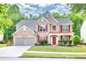 Beautiful two-story brick home with red shutters, landscaped front yard, and spacious garage at 5008 Bethpage Dr, Suwanee, GA 30024